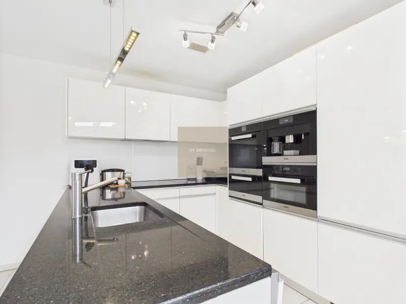 White high-gloss kitchen with granite worktop and built-in appliances